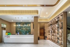 A reception area with a reception desk, a large window, and a bookshelf. - Wuzhou Hotel (Pinghu)