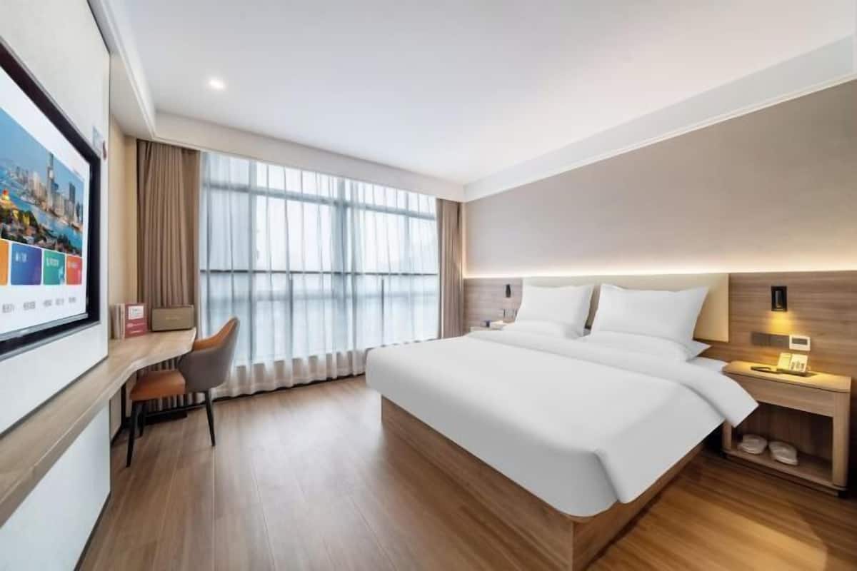 Una habitación de hotel moderna con una cama grande, un escritorio y un televisor montado en la pared.