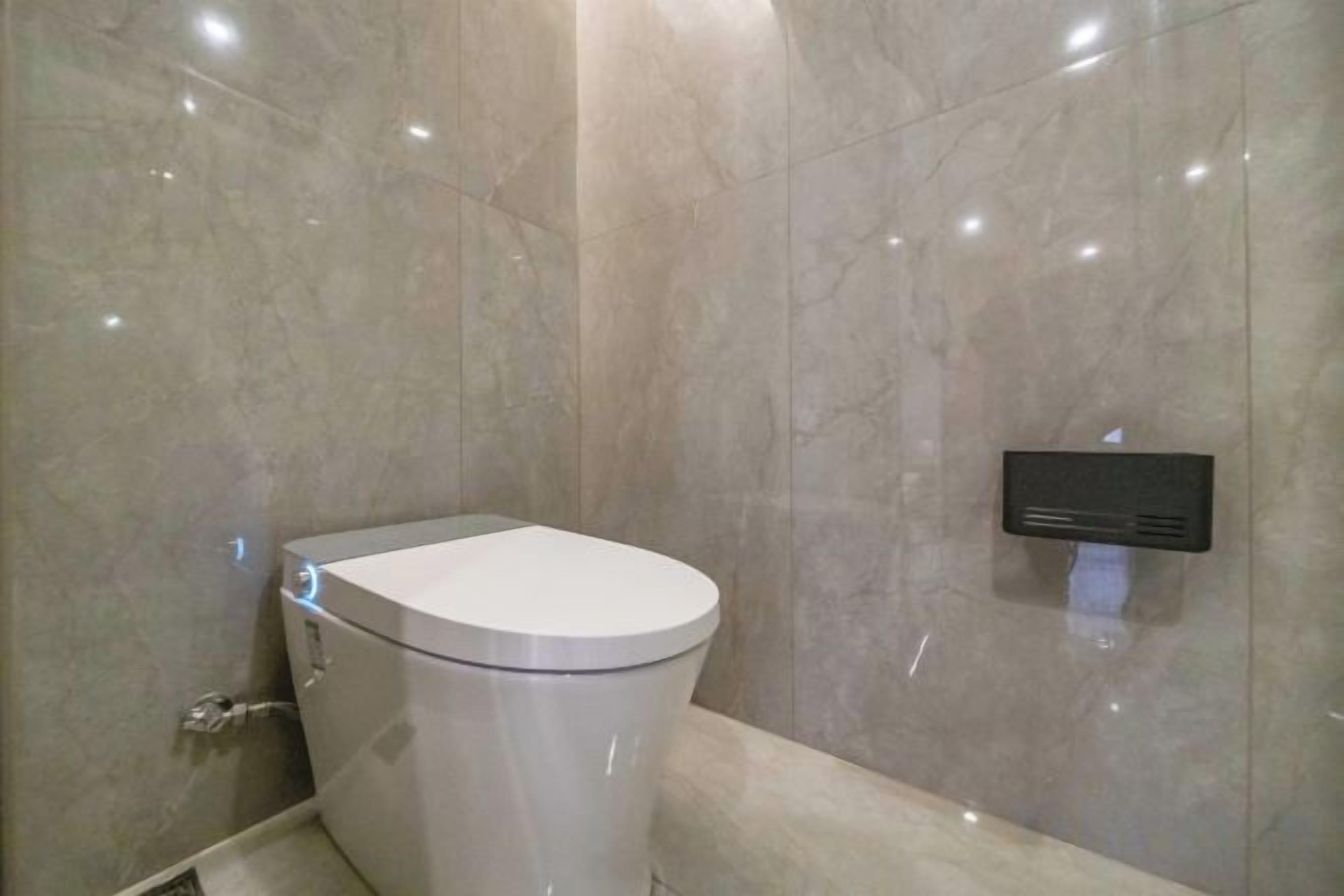 A modern bathroom with a toilet, a wall-mounted bidet, and a marble wall.