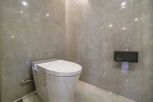 Un baño moderno con inodoro, un bidé empotrado y pared de mármol.