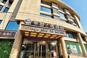 Entrada de un hotel con un letrero que dice 'HUA SHU Y HOTEL' y un escaparate visible con un letrero que dice 'HUA SHU Y HOTEL' a la izquierda.