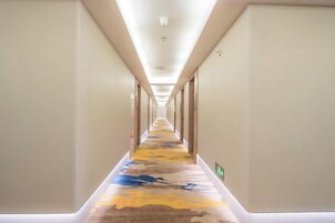 Un pasillo de hotel con piso alfombrado, puertas a ambos lados y una lámpara en el techo.