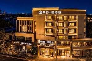 Un hôtel à plusieurs étages doté d’une façade moderne, de nombreux balcons et d’une enseigne lumineuse.