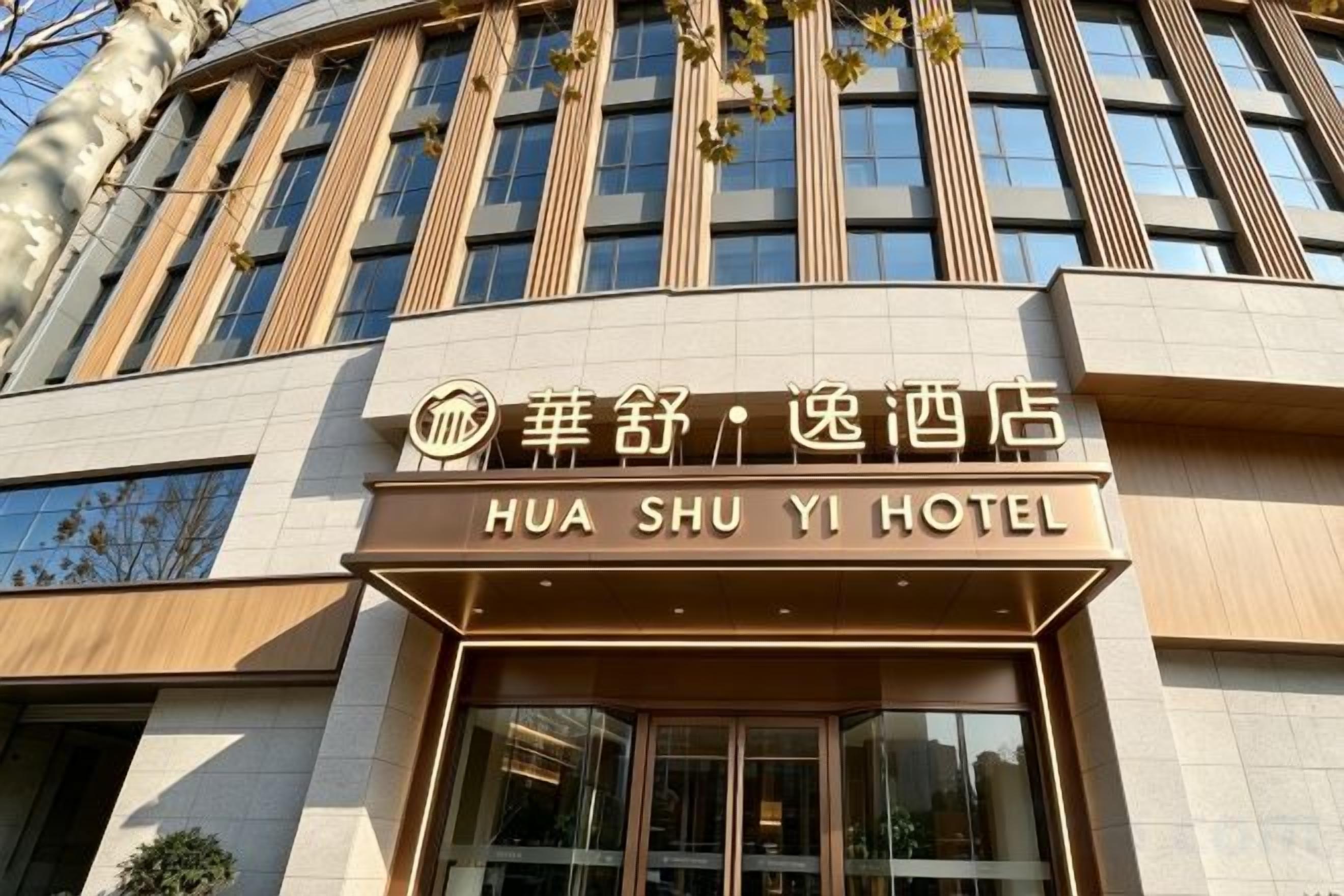 A hotel sign with the name 'HUA SHU YI HOTEL' in both Chinese and English.