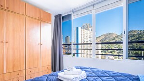 Quarto com uma cama grande, guarda-roupa de madeira e janela com vista para a cidade.