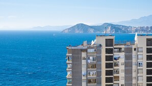 Um edifício alto com varandas com vista para a paisagem costeira e o mar.