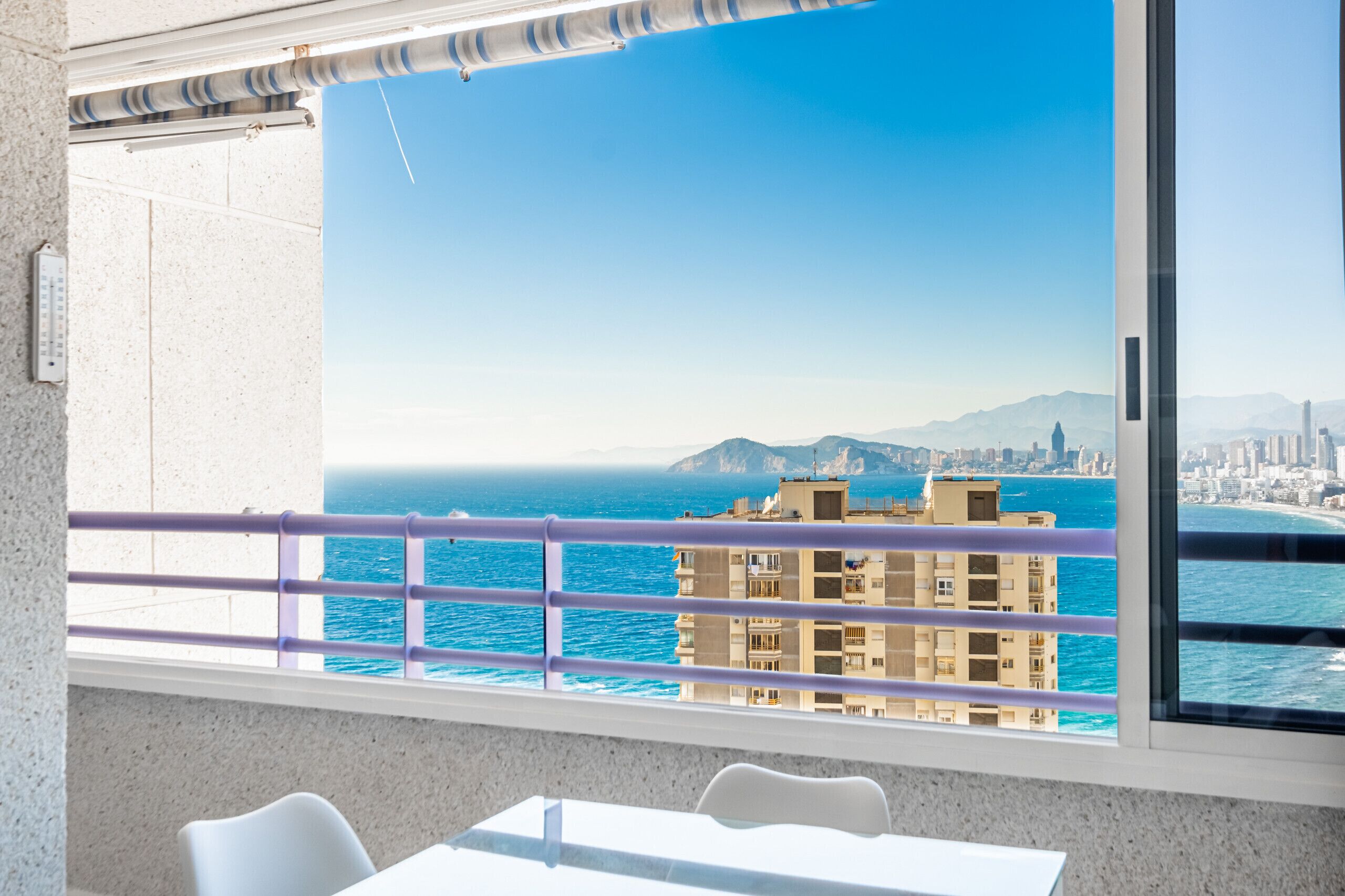 A balcony with a view of the sea and cityscape.