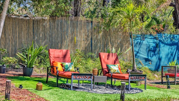 A garden with two red lounge chairs, a small table, and a decorative plant. - Artsy Room with Free Parking (Miami)