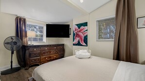 A bedroom with a bed, dresser, fan, TV, window, and artwork. - Artsy Room with Free Parking (Miami)