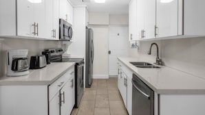 A modern kitchen with white cabinets, stainless steel appliances, and a tiled floor. - Artsy Room with Free Parking (Miami)