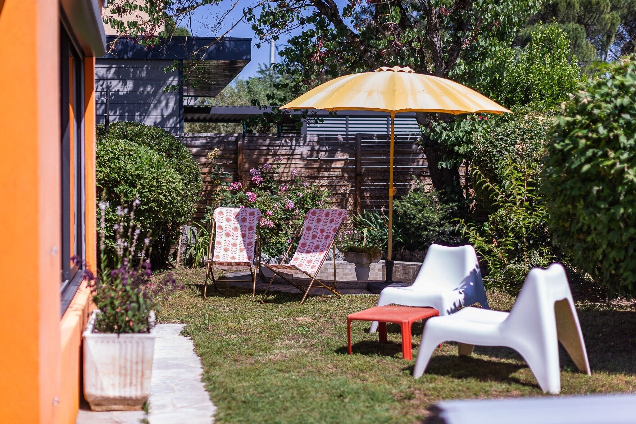 Une terrasse avec deux chaises longues, une petite table et un parasol jaune.