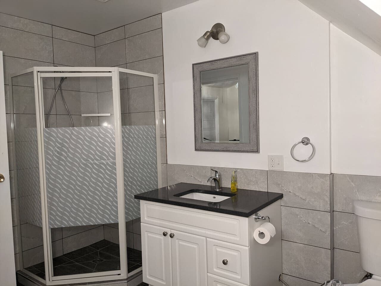 A bathroom with a shower, sink, mirror, and toilet.