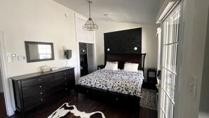 Ein Schlafzimmer mit Bett, Schminktisch, Spiegel und einer Pendelleuchte.