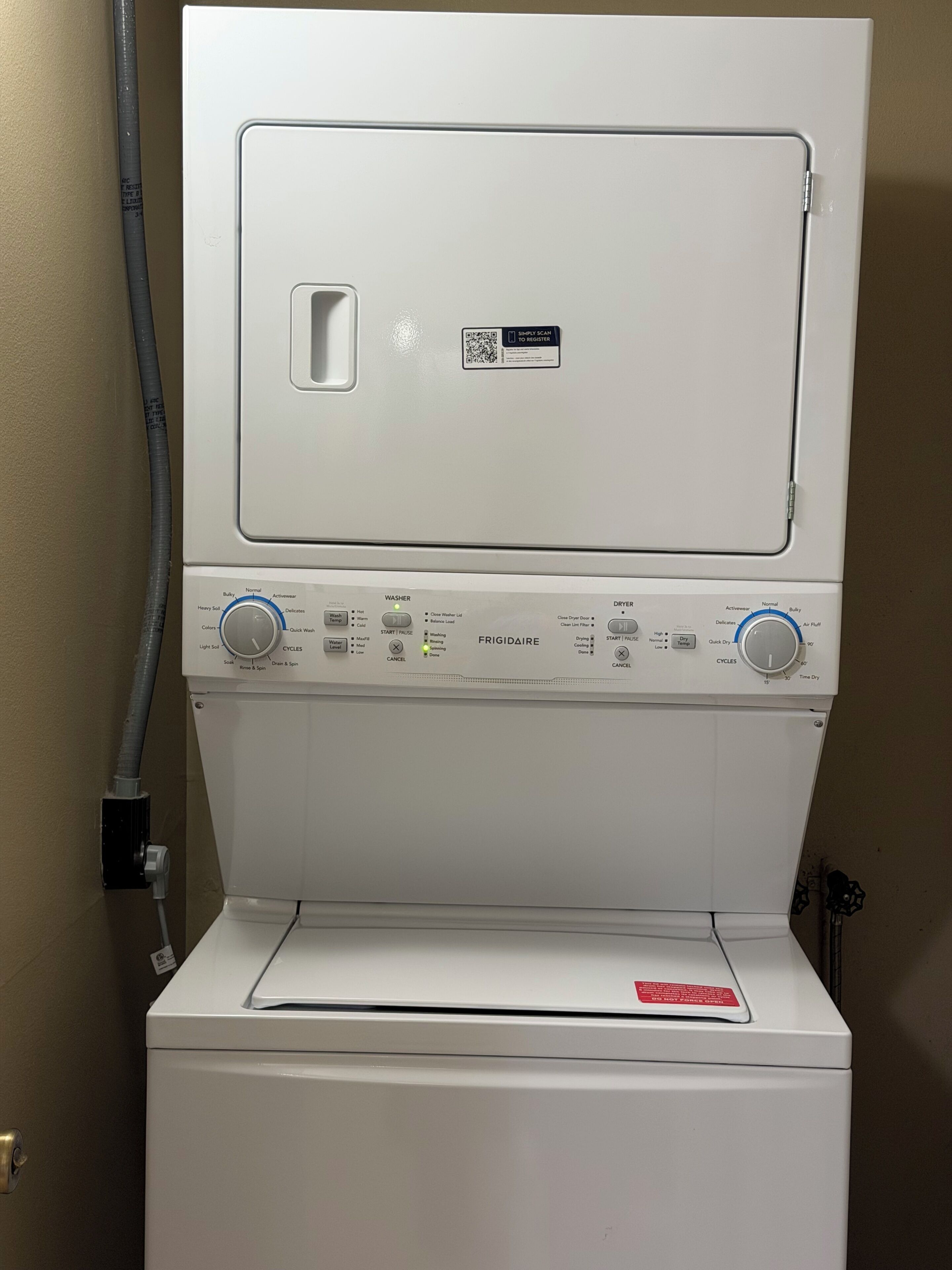 Una lavadora de carga frontal con panel de control, un código QR y una manguera de entrada de agua.