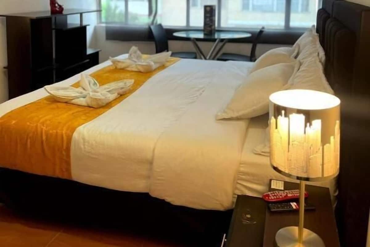 Una habitación de hotel con una cama, un escritorio, un televisor y una ventana.