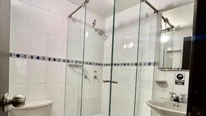 A bathroom with a glass-enclosed shower, a toilet, and a sink. - Studio House Hotel (Bogotá)