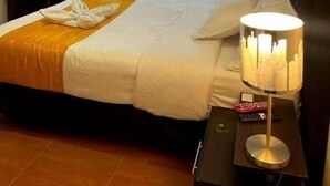A hotel room with a bed, a desk, a TV, and a window with a view. - Studio House Hotel (Bogotá)