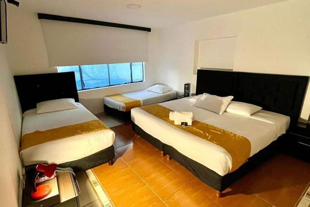 Habitación de hotel con dos camas, una ventana, un escritorio y una silla roja.