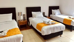 A hotel room with three beds, a nightstand, and a lamp. - Studio House Hotel (Bogotá)