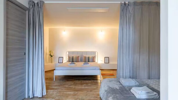 Un dormitorio moderno con una cama grande, mesitas de noche y cortinas.