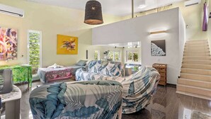 A spacious living area with a large sofa, a hanging light fixture, and artwork on the walls. - Modern Villa with Pool & Garden (Moorea-Maiao)
