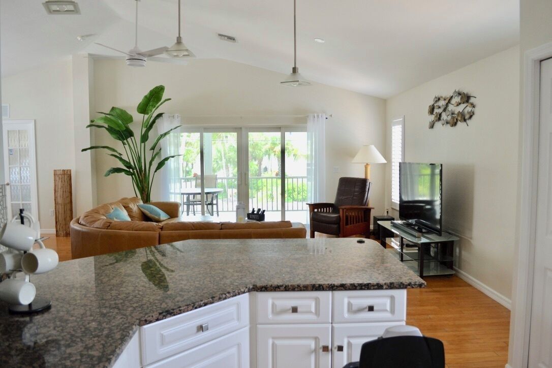 A spacious living area with a kitchen island, a sofa, a dining table, and a television.