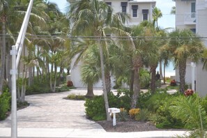 A pathway lined with palm trees and a white mailbox, leading to a building with a balcony. - Barefoot Dreams 100 ft From Beach Mid Island Location Private Pool (Fort Myers Beach)