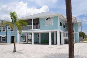 A two-story beachfront property with a balcony, a covered patio, and a small outdoor seating area. - Barefoot Dreams 100 ft From Beach Mid Island Location Private Pool (Fort Myers Beach)