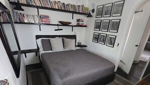 Ein Schlafzimmer mit einem Bett, Bücherregalen, einem Deckenventilator und gerahmten Bildern an der Wand.