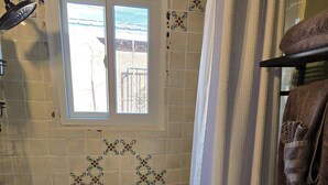Ein Badezimmer mit Badewanne, Dusche und Fenster.