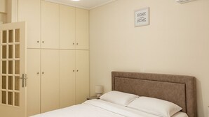 Un dormitorio con cama, armario, mesita de noche, aire acondicionado de pared y lámpara en el techo.