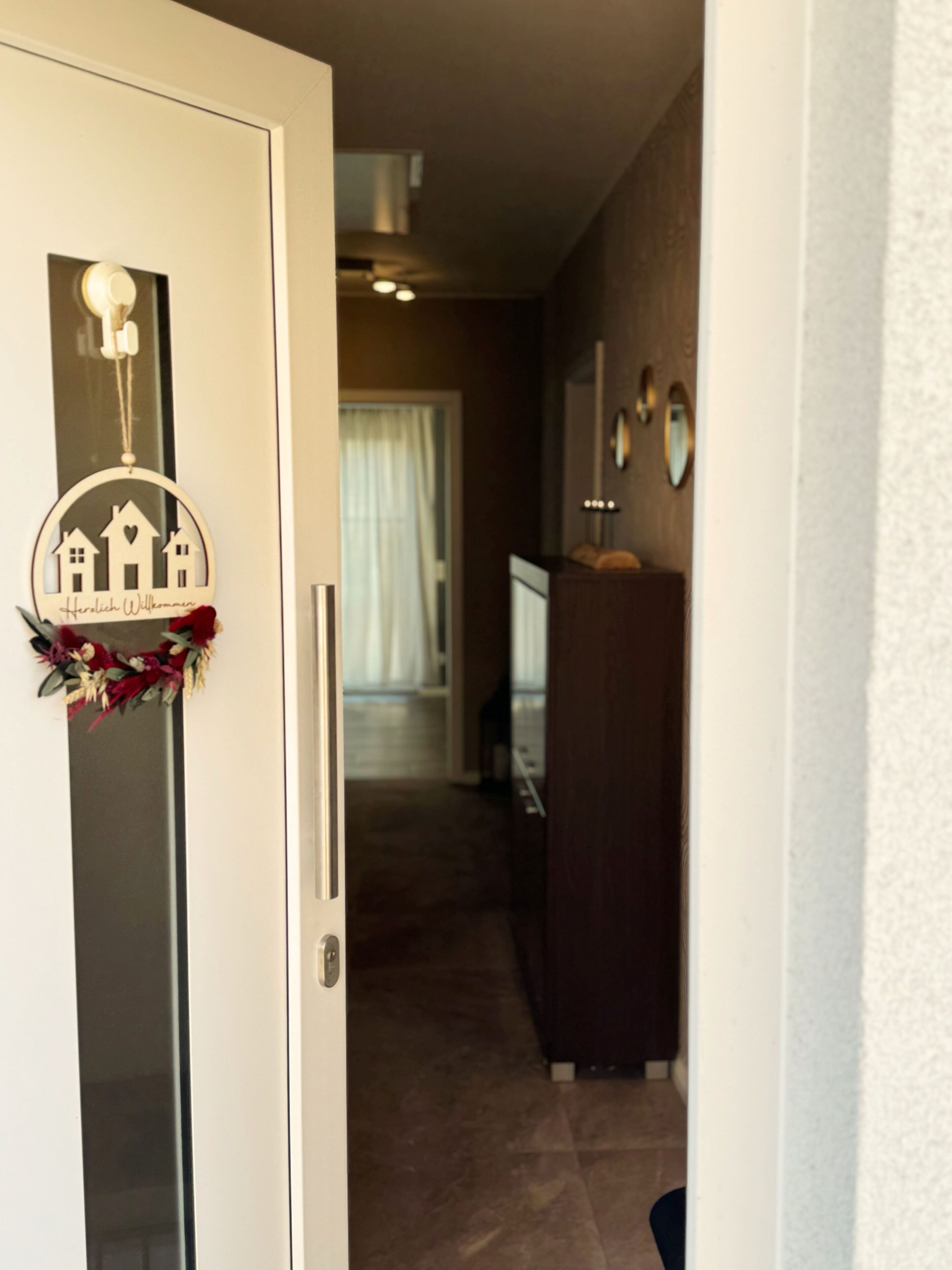 A hallway with a door featuring a welcome sign and a decorative wreath.