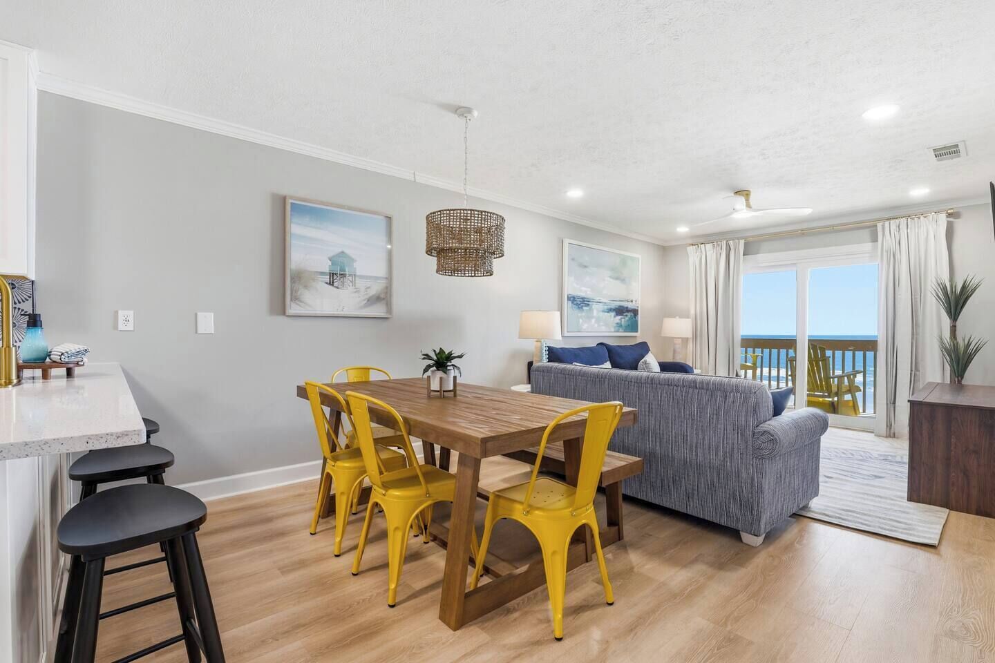 A modern living space with a dining area, sofa, and a balcony with a view.