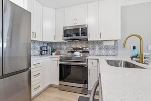 Een moderne keuken met roestvrijstalen apparatuur, witte kasten en een decoratieve achterwand.
