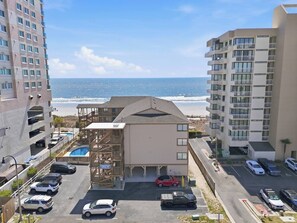 A multi-story building with a pool, parking area, and a view of the ocean. - Oceanfront NEW Updated Modern Condo w/ 4 Beds! (North Myrtle Beach)