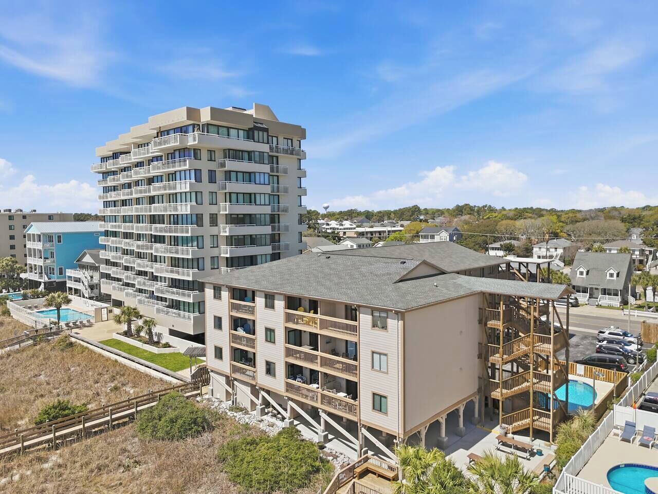 Un hotel de varios pisos con balcones, piscina y vista al mar.