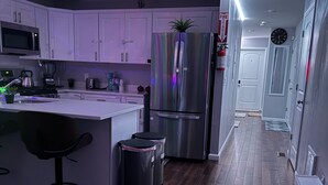 Una cucina moderna con mobili bianchi, elettrodomestici in acciaio inossidabile e un'isola centrale con sgabelli da bar.