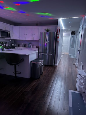 Cocina moderna con armarios blancos, electrodomésticos de acero inoxidable y una isla central con taburetes de bar.