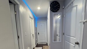 Un corridoio con pavimento in legno, pareti bianche e un orologio appeso al muro.