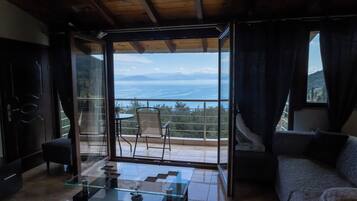 A modern living room with a glass coffee table, a sofa, and a view of the sea.