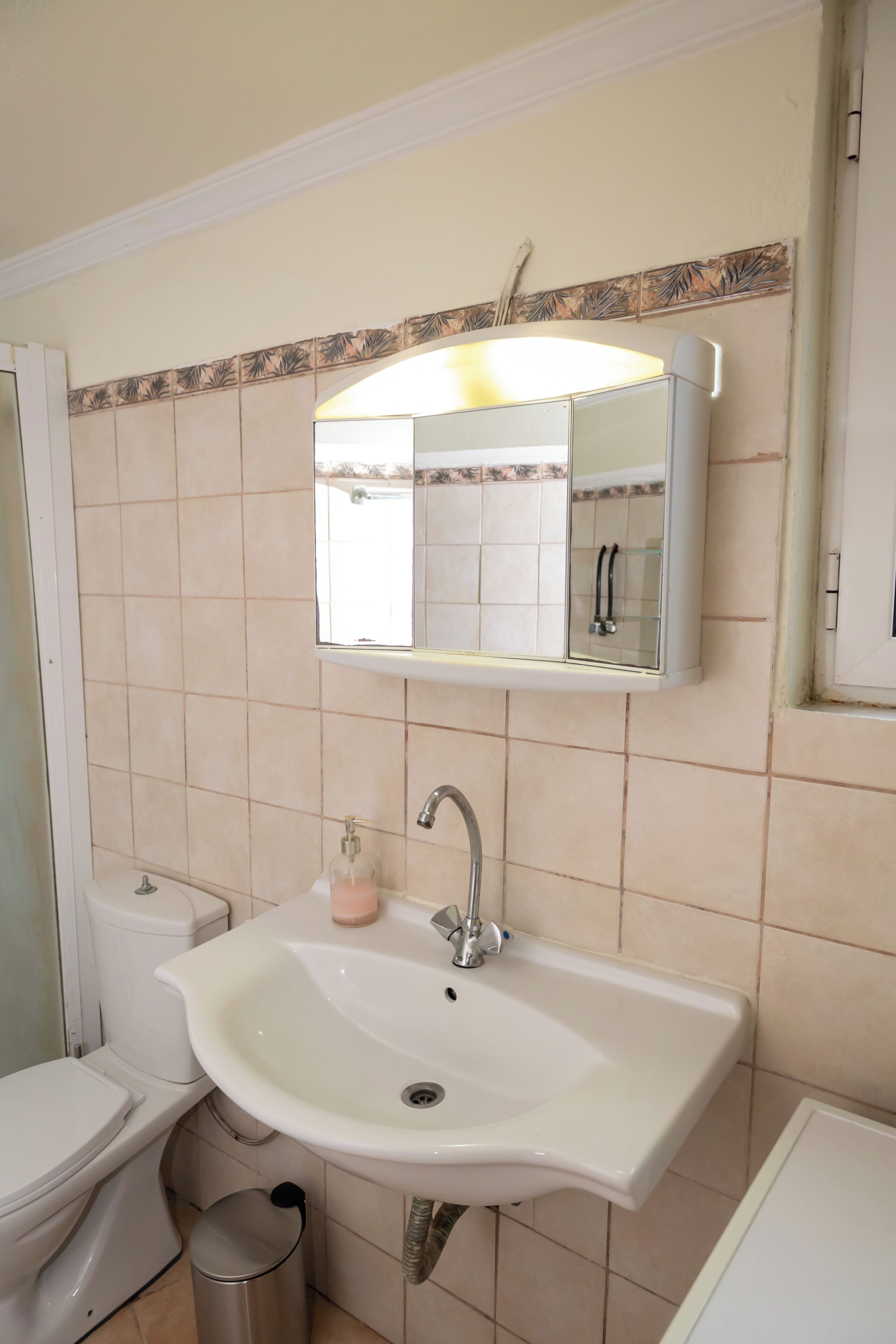 A bathroom with a white sink, a mirror, and a toilet.