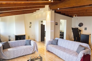 A spacious living area with two sofas, a fireplace, and wooden beams on the ceiling. - Ionian Skyline Horizon House by ΜΡS (Loukata)