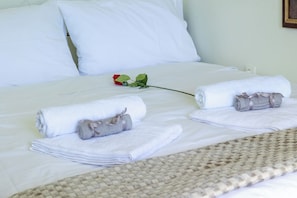 A neatly made bed with white linens, a rolled towel, and a single red rose. - Ionian Skyline Horizon House by ΜΡS (Loukata)