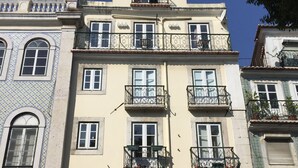 Un edificio de varios pisos con balcones, una tienda en la planta baja y un cartel que indica un mercado.