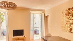 Una sala de estar moderna con piso de madera, una mesa de comedor con sillas, un televisor y un adorno de pared.