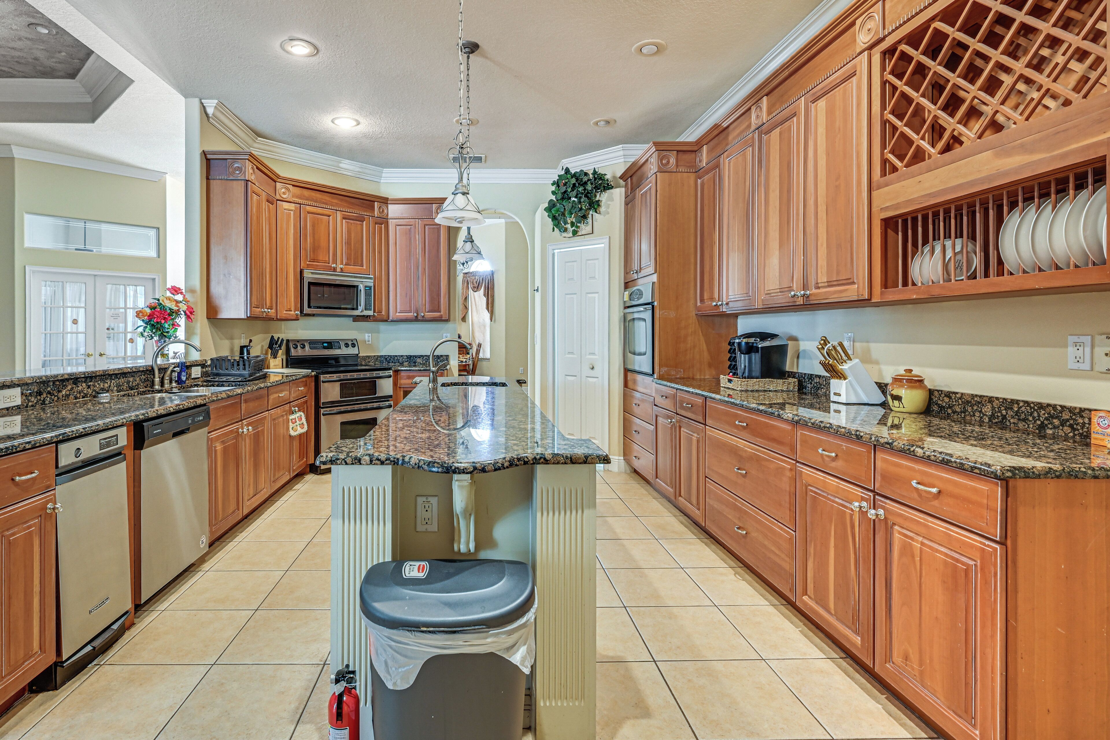 A kitchen with wooden cabinets, granite countertops, a central island, and a microwave.