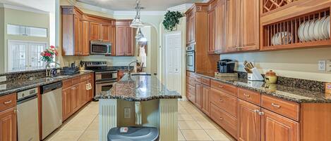 A kitchen with wooden cabinets, granite countertops, a central island, and a microwave.