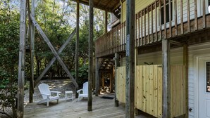 A wooden deck with two white chairs and a door leading to a covered area. - Sandpiper Hideaway - Easy Beach Access (Indian Beach)