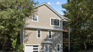 A two-story house with a front porch, a garage, and a fenced yard. - Sandpiper Hideaway - Easy Beach Access (Indian Beach)