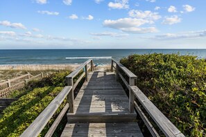 A wooden boardwalk leading to a beach with a clear view of the ocean.